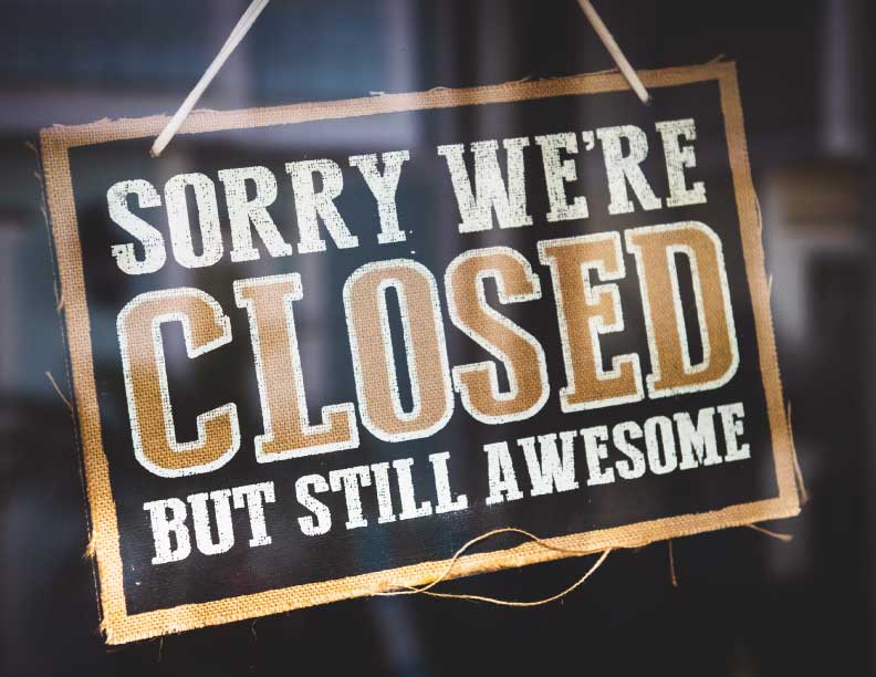 A sign hanging in a window and reading 'Sorry, we're Closed, but still awesome'