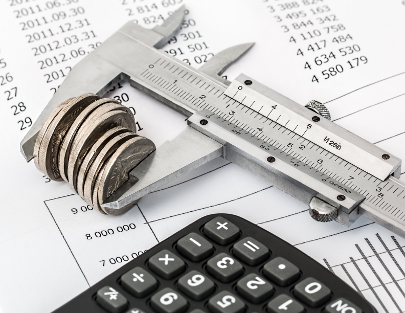 A small stack of coins being measured in a vernier caliper, laying on a financial document